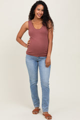 woman wearing a rust-colored maternity tank top and blue skinny jeans, showing her baby bump