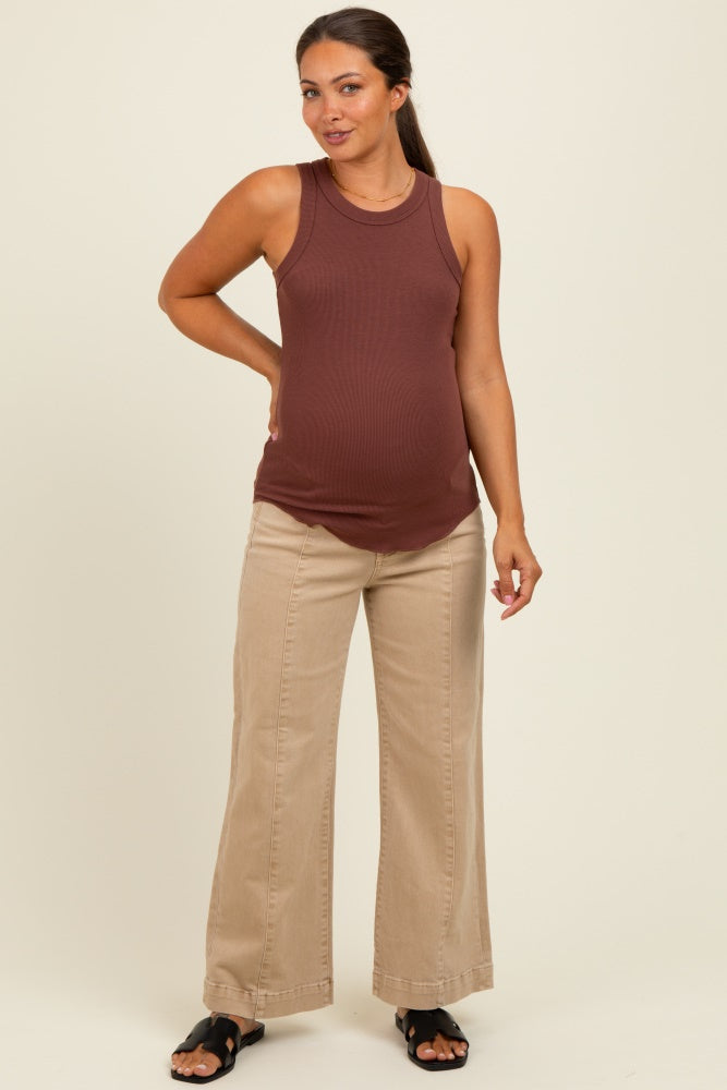 woman wearing a rust ribbed maternity tank top and beige wide-leg pants with a visible baby bump