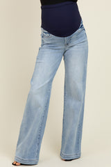 woman wearing light blue wide-leg maternity jeans with a black belly band, highlighting her baby bump