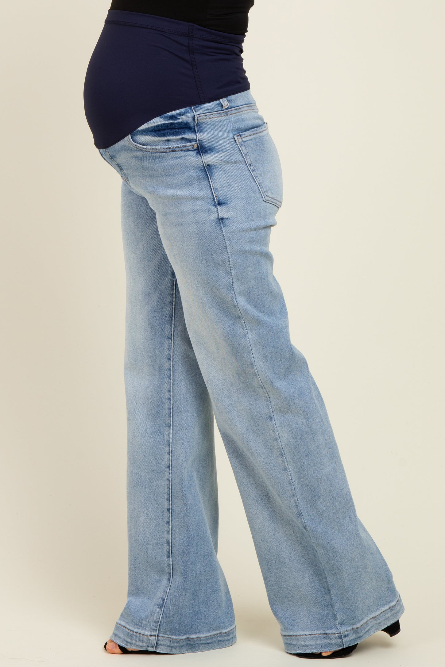 maternity wear featuring a pregnant model in light wash flared jeans with a soft waistband accommodating a baby bump