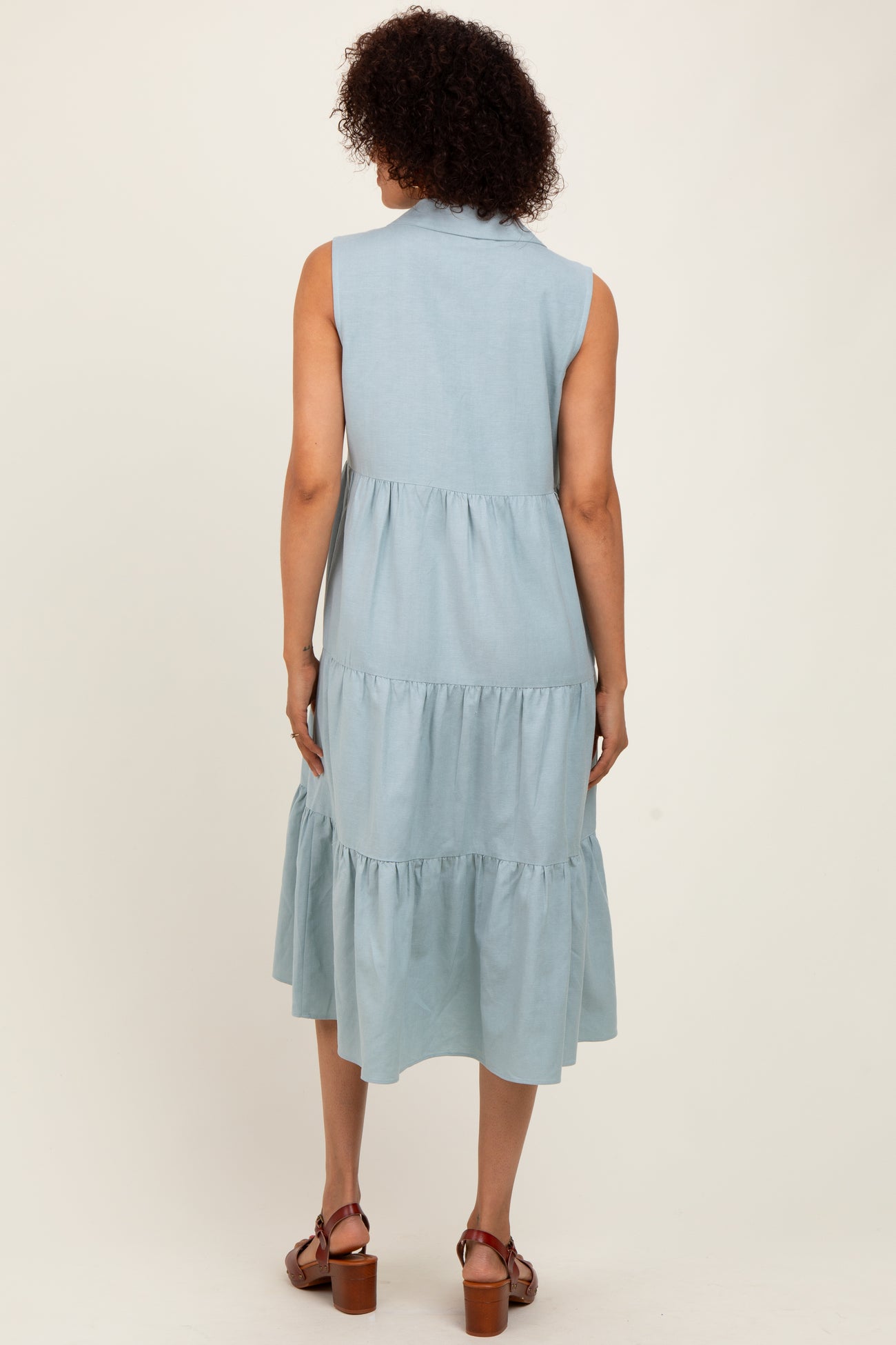 woman wearing a sleeveless light blue tiered midi dress, view of the back and shoulder details
