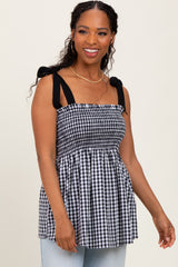 woman wearing a black and white gingham print peplum top with tie straps and smiling