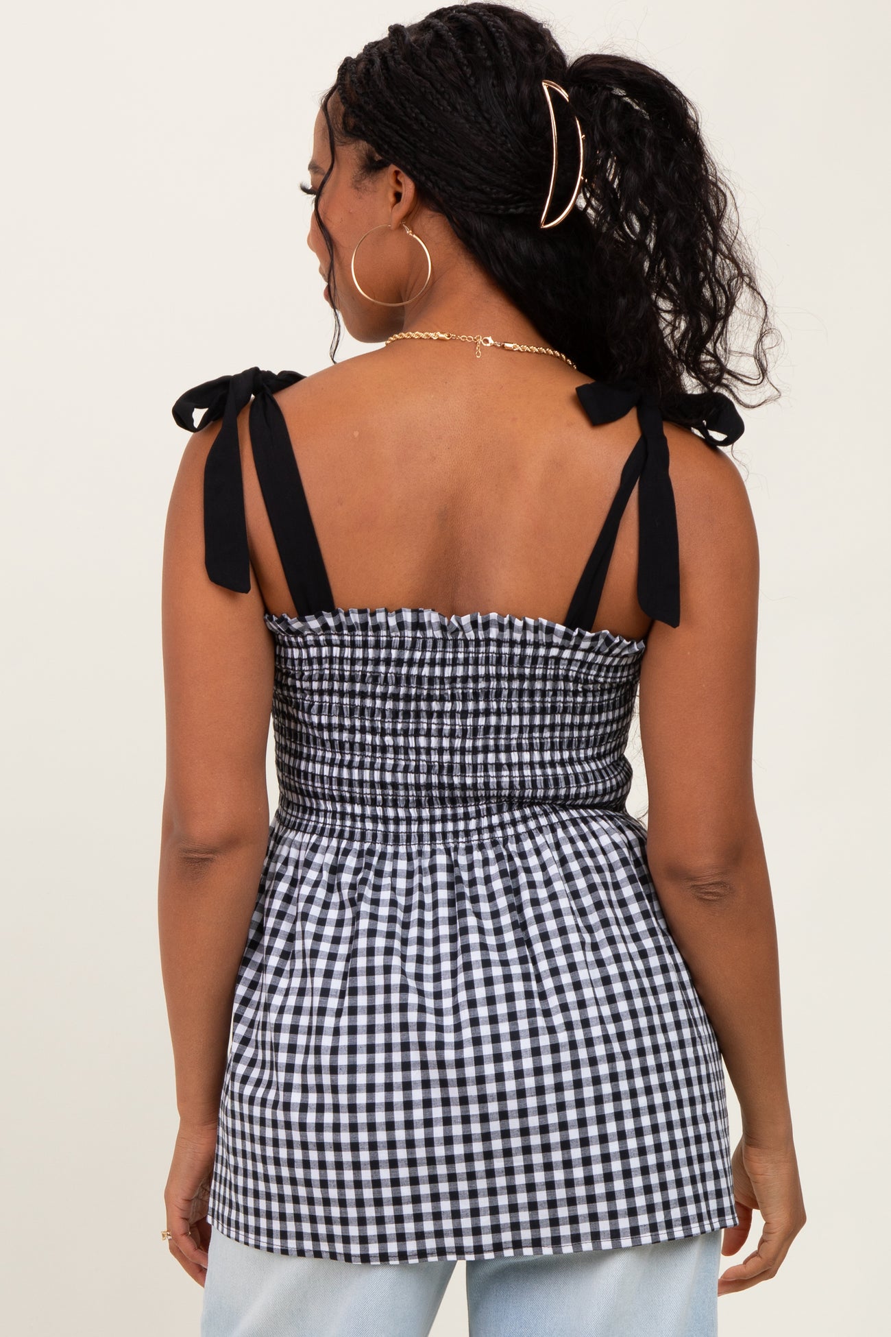 woman wearing a black and white gingham smocked top with tie shoulder straps and a fitted bodice