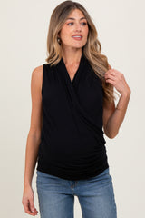 woman wearing a black sleeveless maternity top with a wrap design and gathered detailing, showing a baby bump