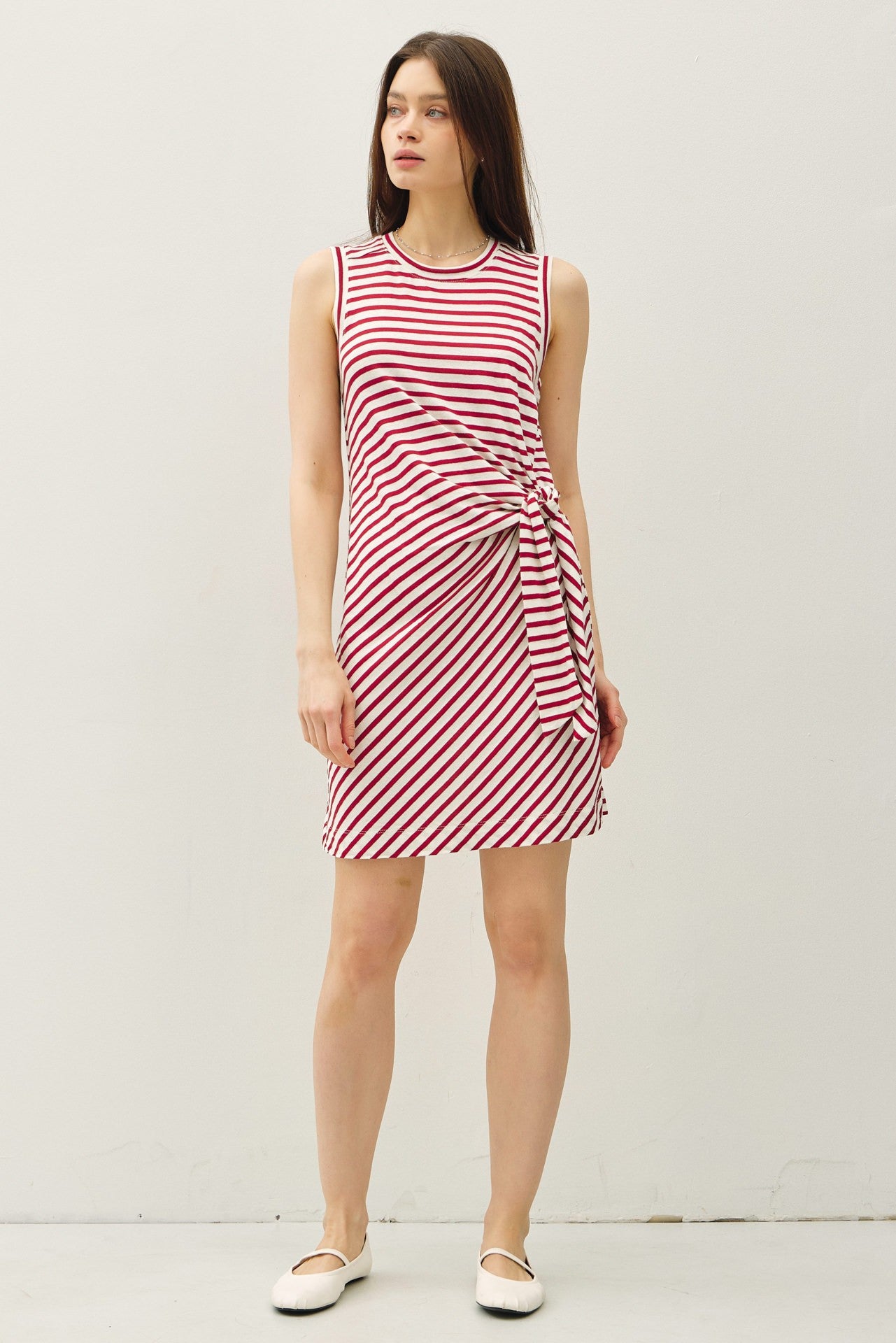 woman wearing a red and white striped sleeveless dress with a side knot detail