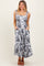 woman wearing a floral print maxi dress with tie straps and pockets, styled with brown heeled sandals
