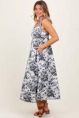 woman wearing a floral print maxi dress with tie shoulder straps and pockets, standing sideways