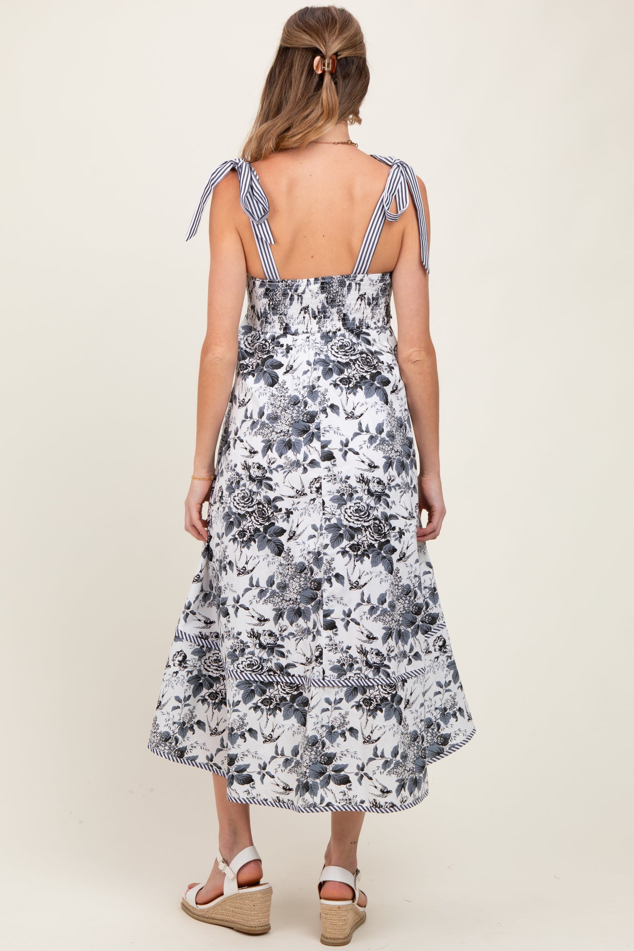 woman wearing a floral print maternity dress with back tie details and a flowing skirt