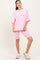 woman wearing a pink oversized t-shirt with pocket and matching pink bike shorts, styled with white sneakers