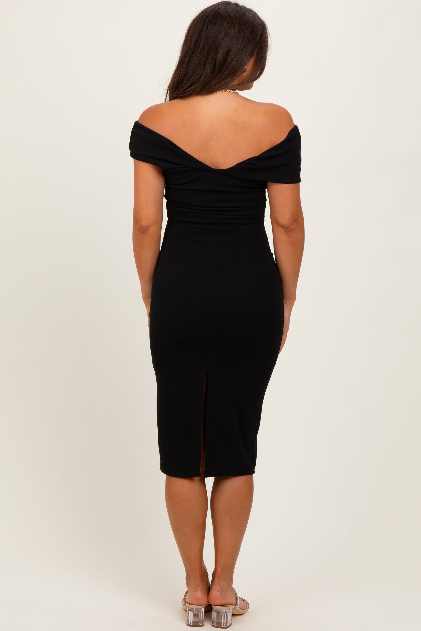 woman wearing a black off-shoulder maternity dress with a fitted silhouette and a back slit