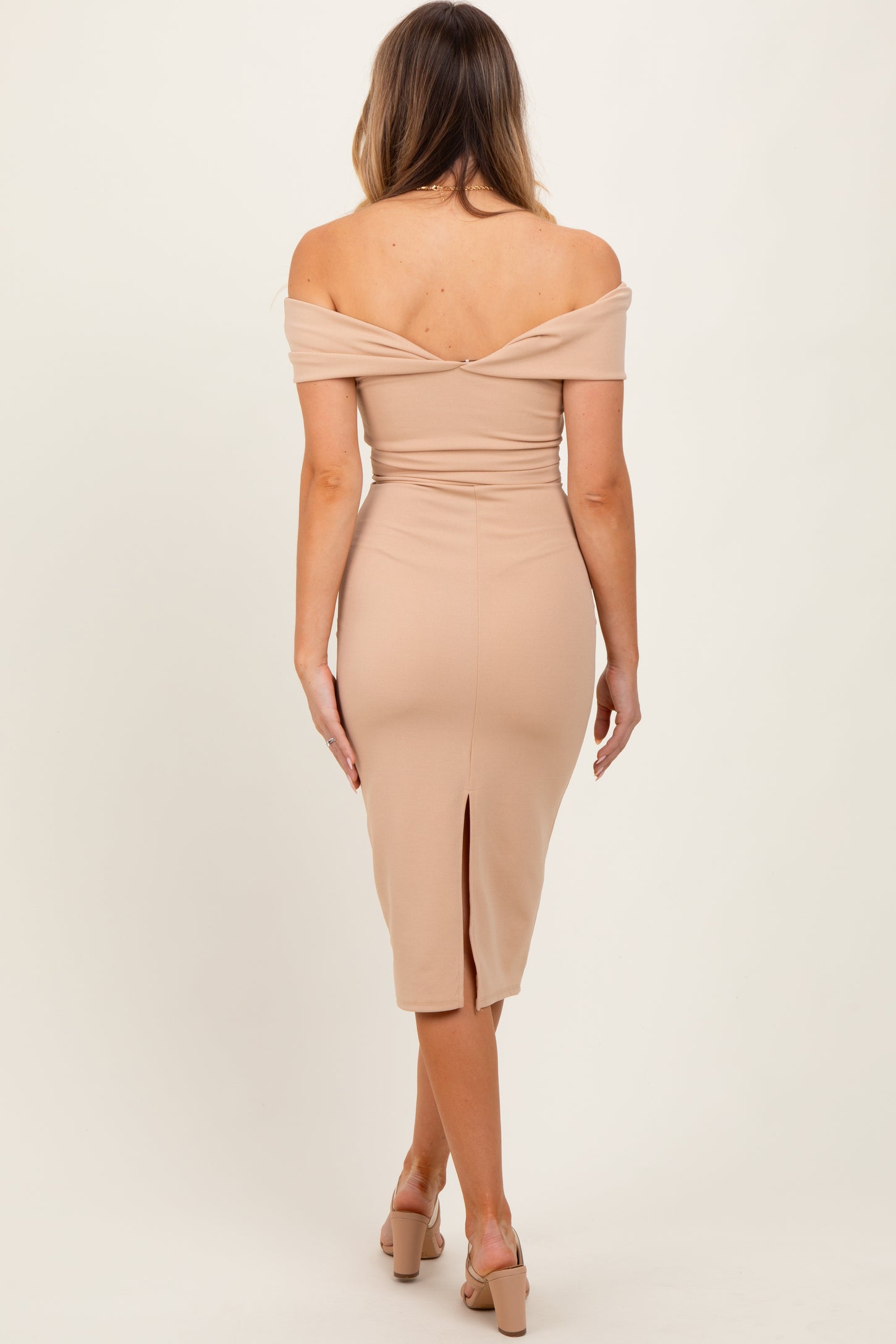 woman wearing a beige off-the-shoulder bodycon dress with a back slit, showing her bare back