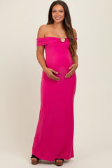 woman wearing a bright pink off-the-shoulder maternity dress, holding her baby bump