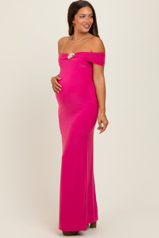 woman wearing a hot pink off-the-shoulder maternity gown with ruching and a decorative detail, showing her baby bump