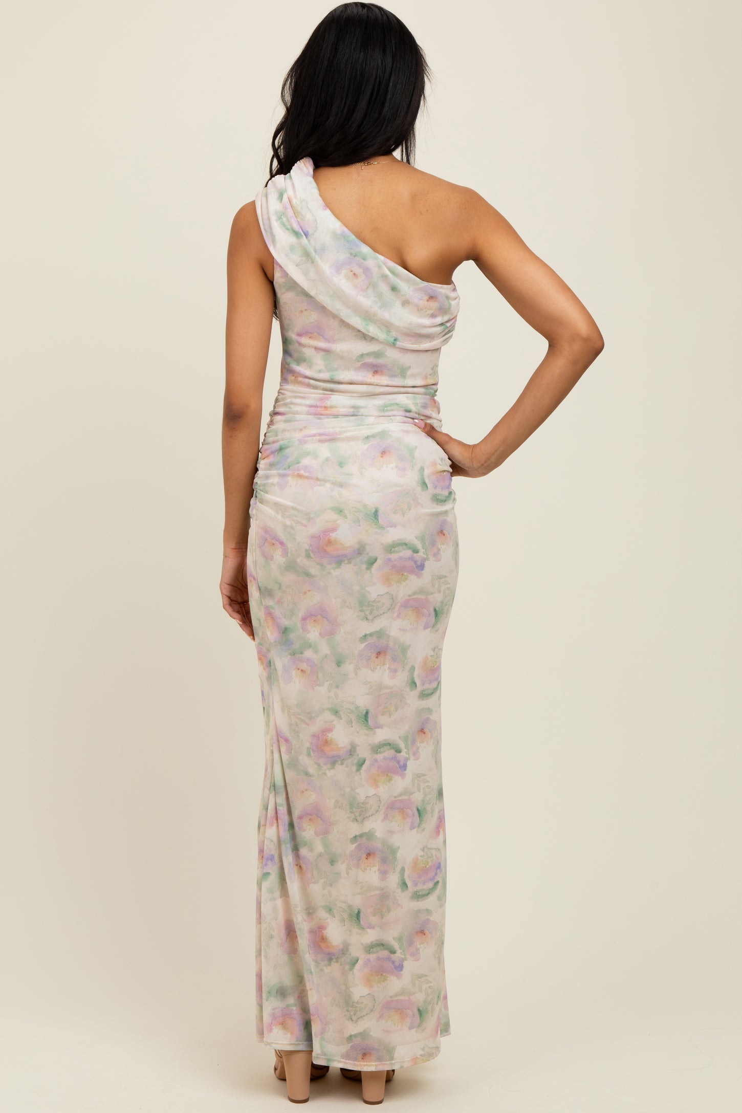 woman wearing a pastel watercolor print one-shoulder maxi dress showcasing a fitted silhouette from the back