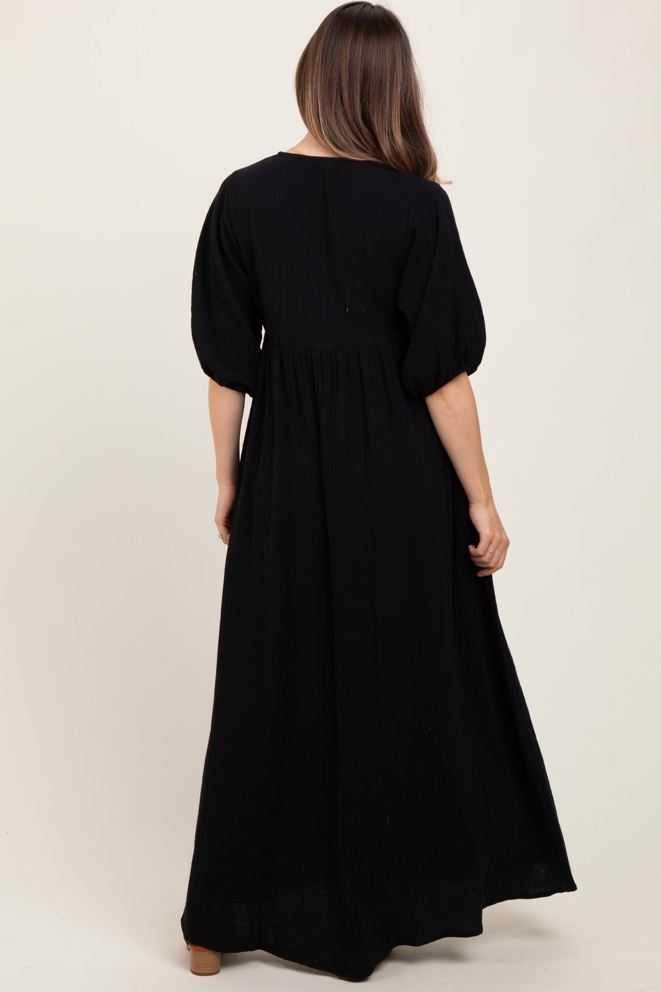 woman wearing a black puff sleeve maxi maternity dress, visible baby bump from the back