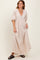 woman wearing a beige maxi dress with a v-neckline and puff sleeves, standing casually