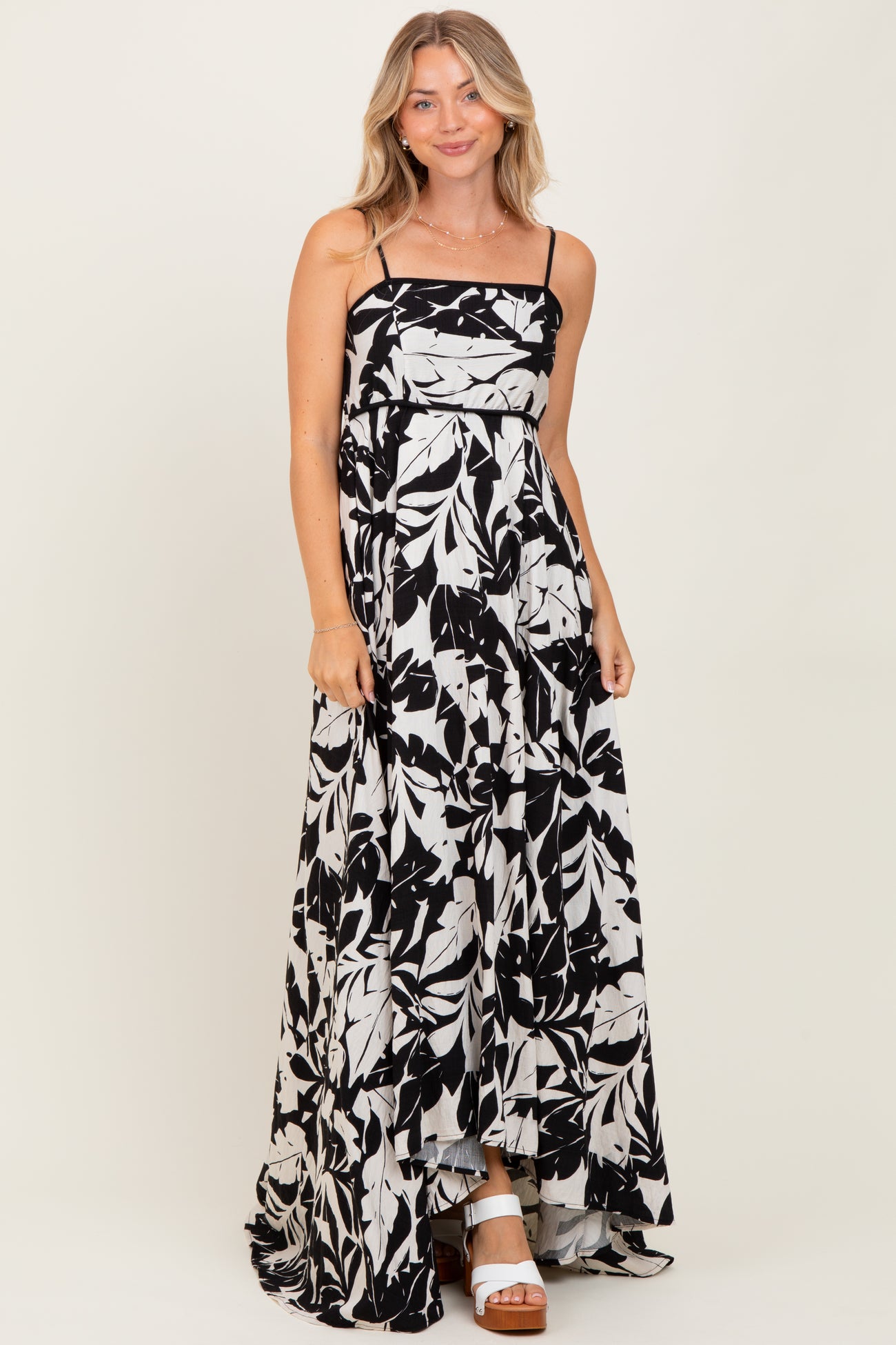 woman wearing a black and white floral maxi dress with spaghetti straps and a flowy skirt