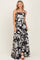 woman wearing a black and white floral maxi dress with spaghetti straps and a flowy skirt