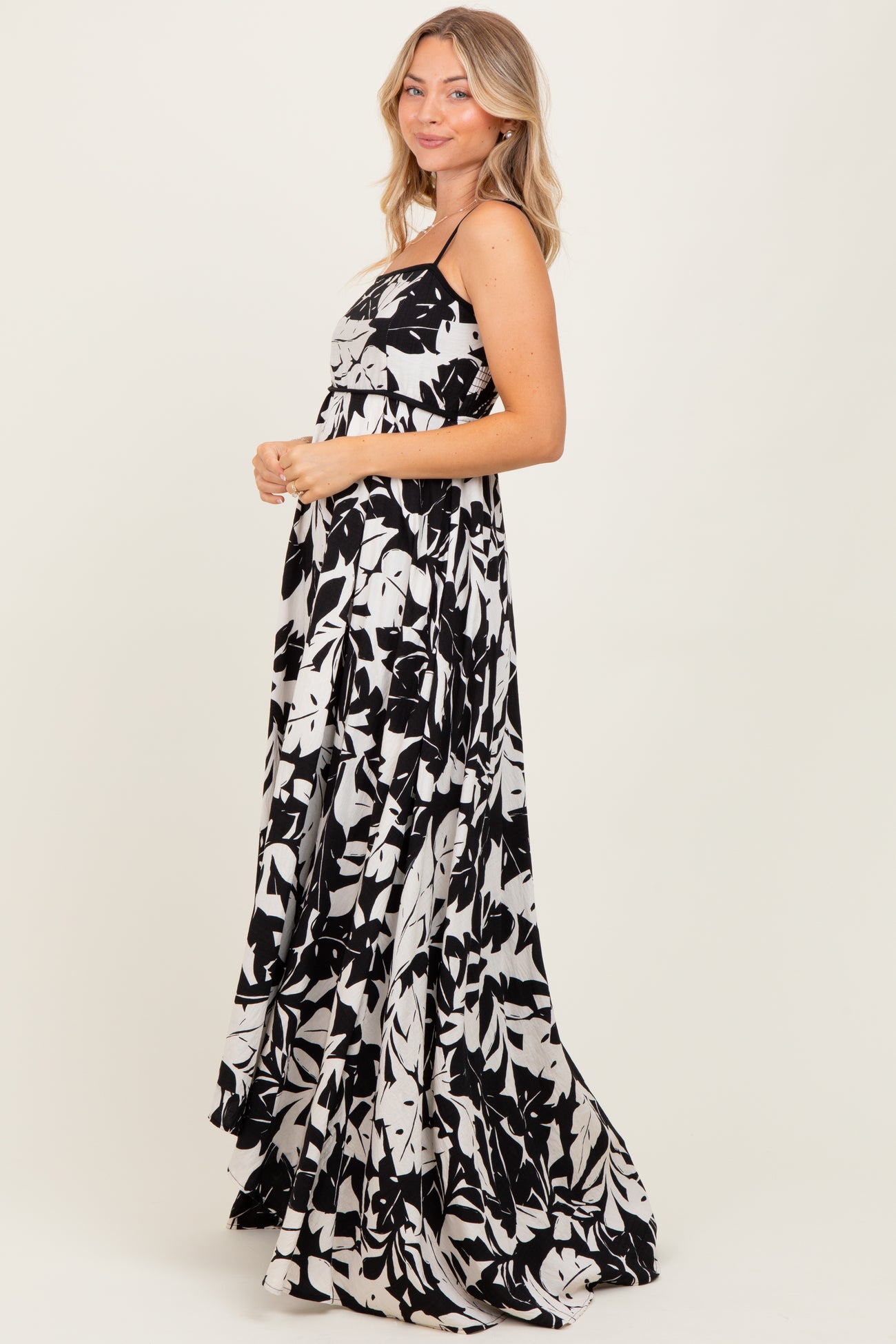 woman wearing a black and white floral maxi dress with a flowy skirt and adjustable straps
