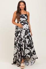 woman wearing a black and white floral print maternity maxi dress, holding her baby bump