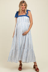 woman wearing a blue and white patterned maternity dress with tie straps and a visible baby bump