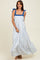 woman wearing a white and blue patterned maxi dress with bow tie straps and a flowing silhouette