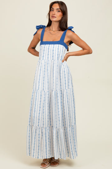 woman wearing a white and blue floral print maxi dress with square neckline and bow-tie straps