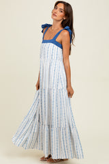 woman wearing a blue and white floral maxi dress with tie shoulder straps and a tiered skirt
