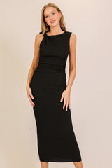 woman wearing a black sleeveless midi dress with a ruched design and a shoulder knot detail