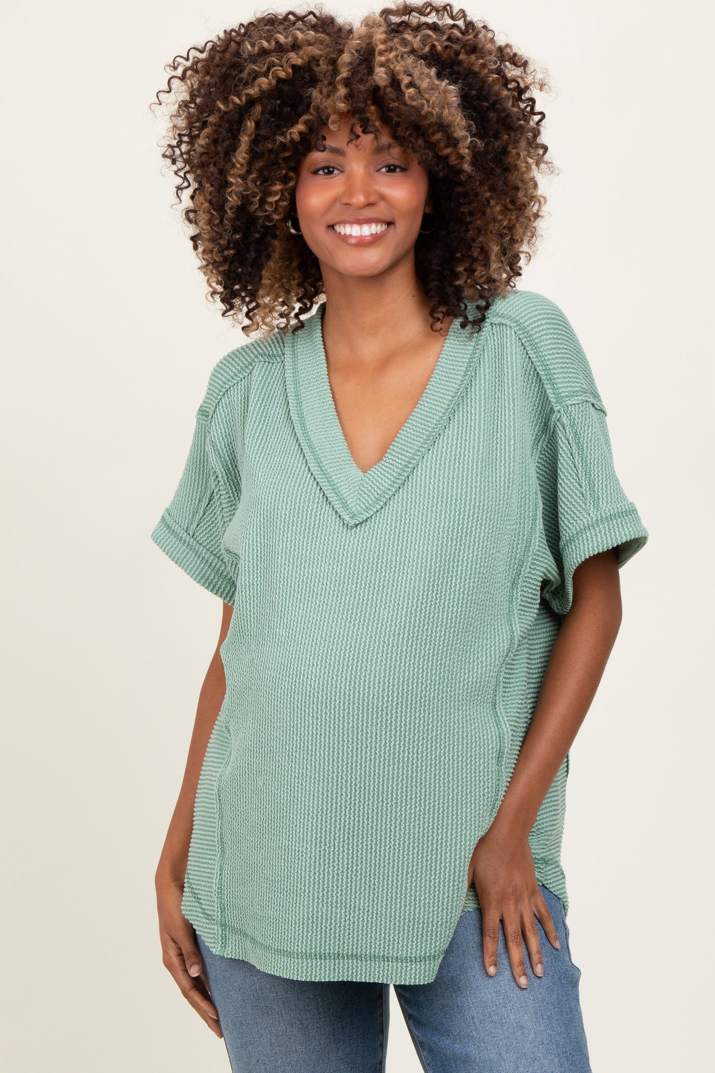 woman wearing a green v-neck maternity top with short sleeves and a visible baby bump
