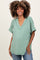 woman wearing a green v-neck maternity top with short sleeves and a visible baby bump