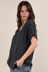woman wearing a dark gray oversized short sleeve top with a v-neck and textured fabric