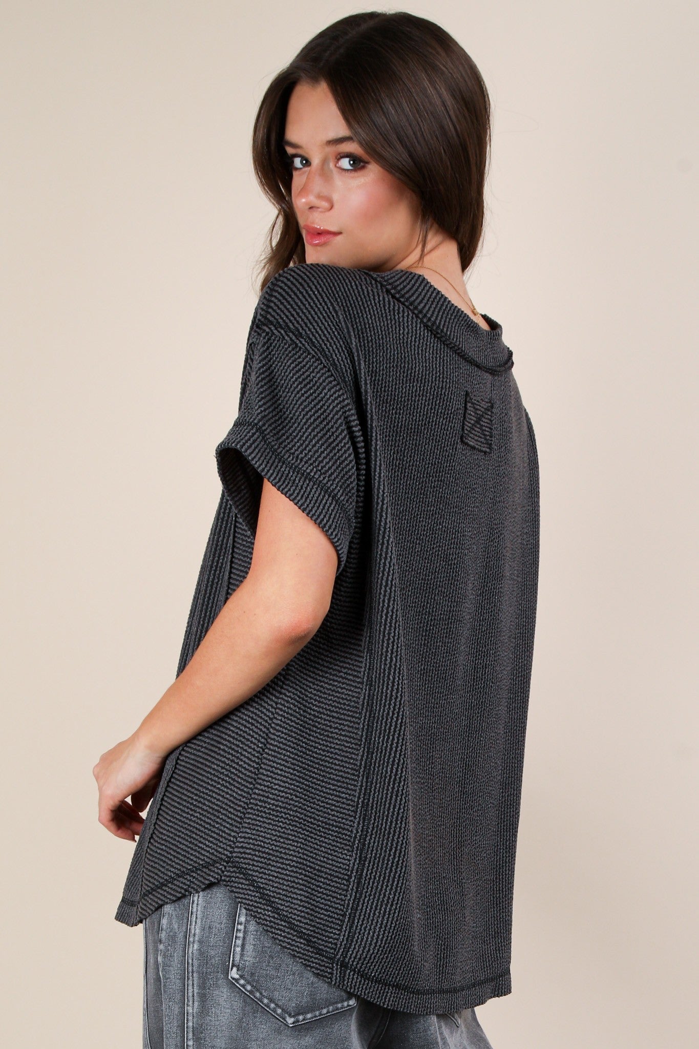 woman wearing a black textured short sleeve top with a relaxed fit and a back logo detail