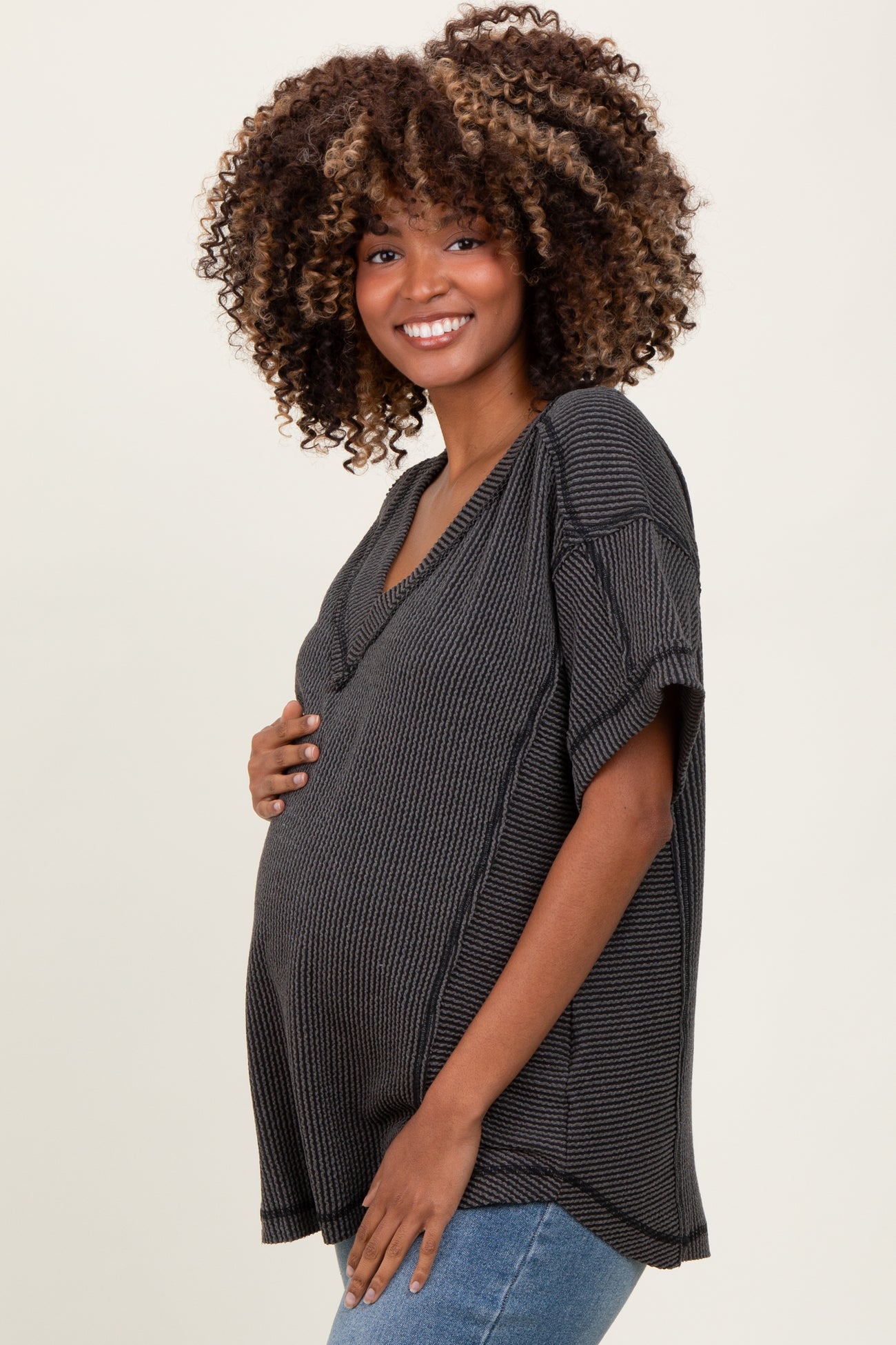 woman wearing a dark gray ribbed maternity top and holding her baby bump