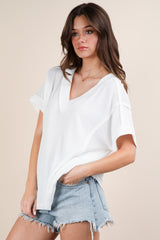 woman wearing a white oversized v-neck knit top paired with light wash denim shorts