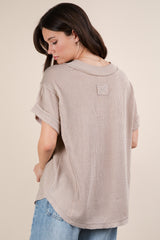 woman wearing a taupe oversized knit sweater with rolled sleeves and a round neckline, shown from the back