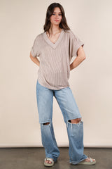 woman wearing a ribbed beige v-neck top and distressed oversized light blue jeans