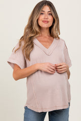 woman wearing a light pink v-neck short sleeve maternity top with a visible baby bump