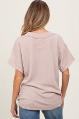 woman wearing a light pink oversized maternity top with a textured pattern, seen from the back