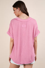 woman wearing a pink oversized knit top with short sleeves and a relaxed fit, seen from the back