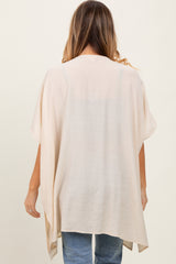 woman wearing a neutral beige open-front kimono style top with loose sleeves and a relaxed fit