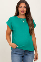 woman wearing a green short sleeve maternity top and casual jeans, showing off her baby bump
