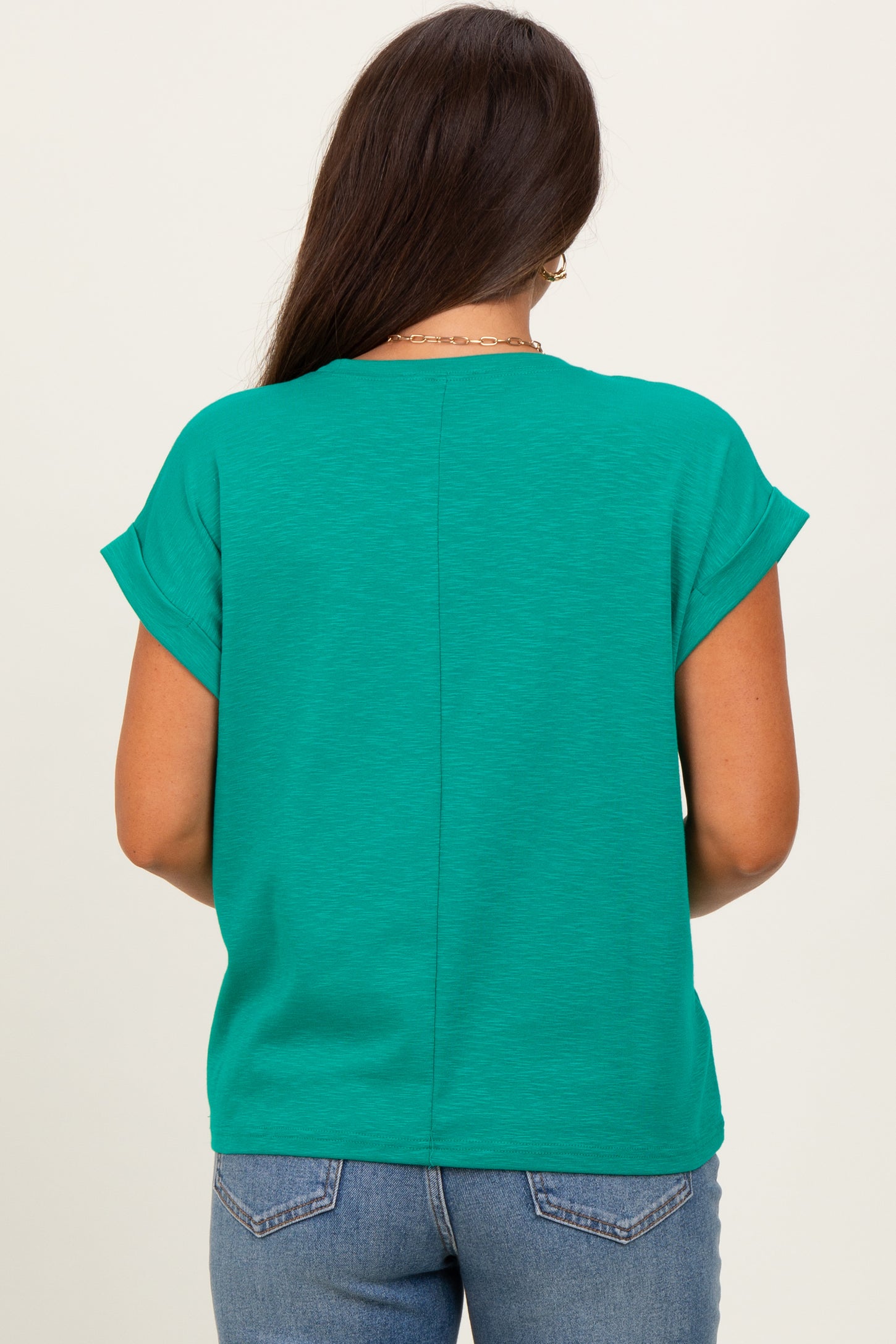 woman wearing a green short sleeve maternity top viewed from the back with a straight seam detail