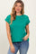 woman wearing a green short sleeve top with rolled cuffs and styled with blue jeans
