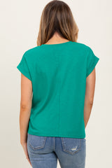 woman wearing a green short sleeve top with a relaxed fit and back seam detail, paired with blue jeans