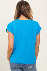 woman wearing a bright blue short sleeve top, view from the back, paired with light wash denim jeans