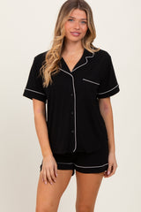woman wearing a black short sleeve pajama set with white piping and a pocket