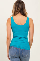 woman wearing a turquoise fitted tank top paired with light blue jeans, shown from the back
