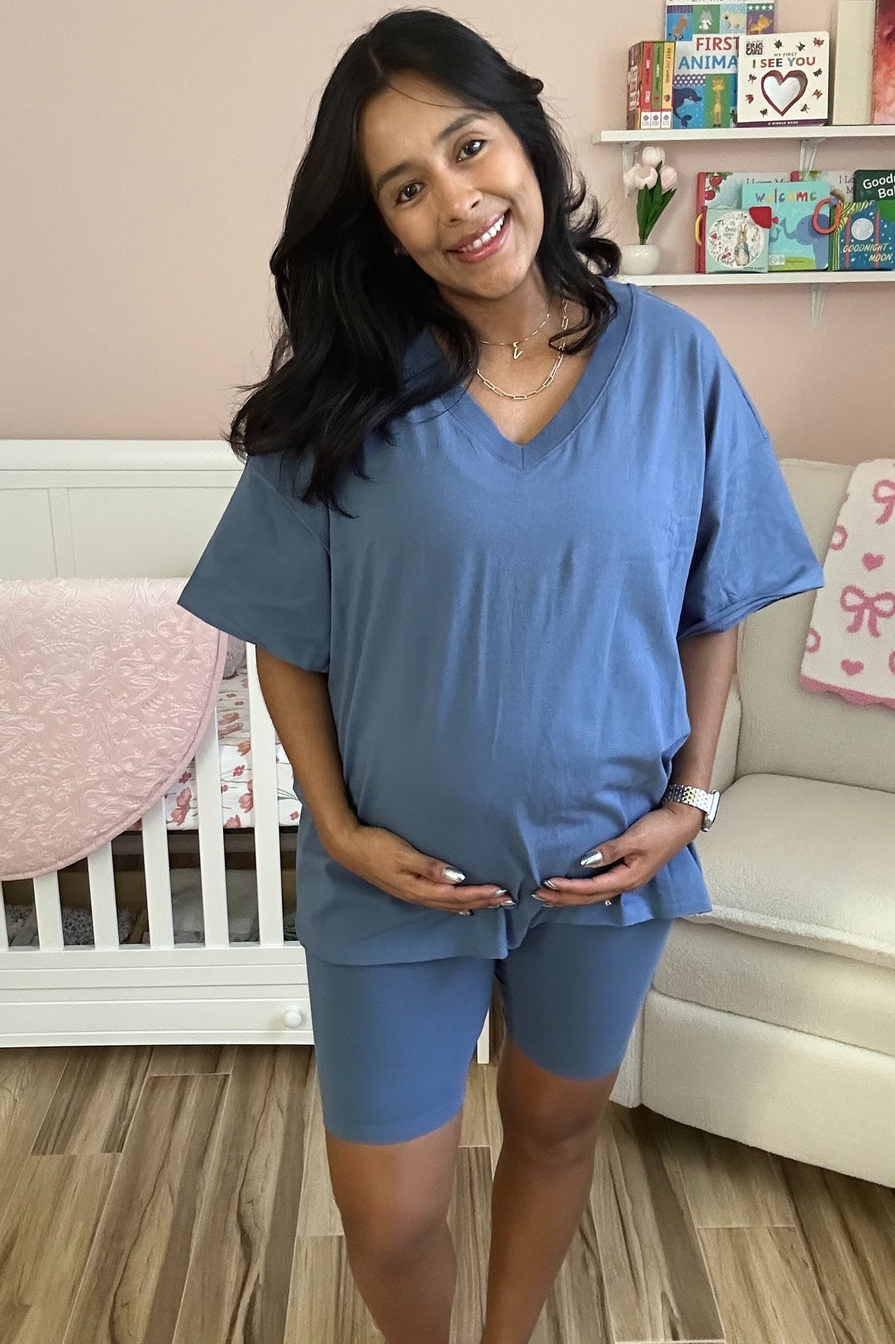 woman wearing a blue maternity short set and holding her baby bump