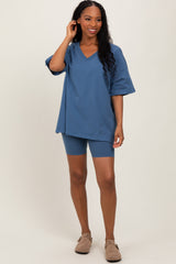woman wearing a blue oversized v-neck top with short sleeves and matching bike shorts, standing and smiling